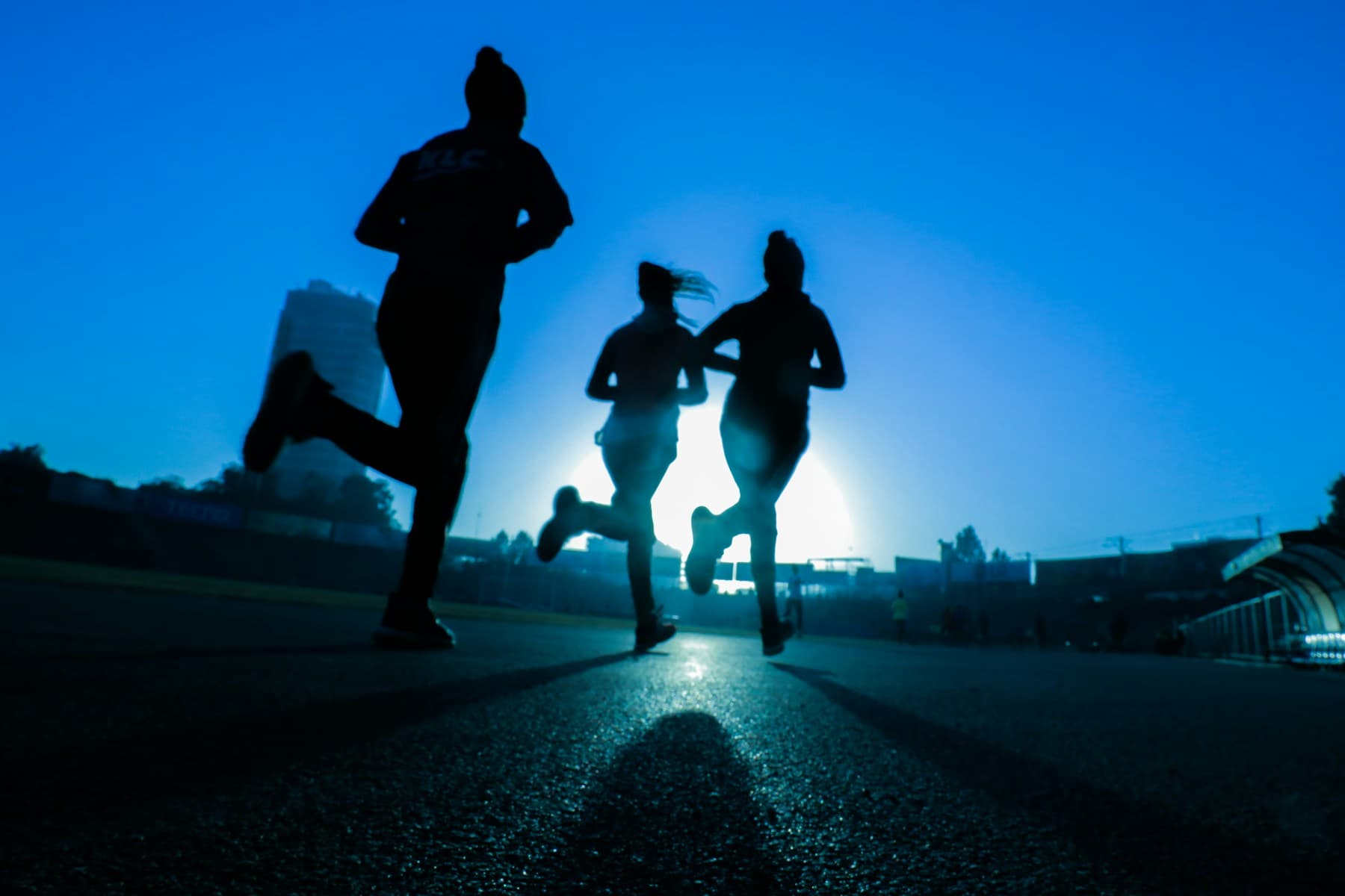 A runner moving along an open road in daylight.